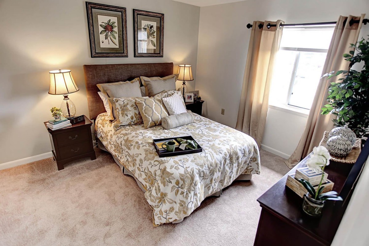A cozy bedroom with a neatly made bed, soft lighting, and decorative artwork.