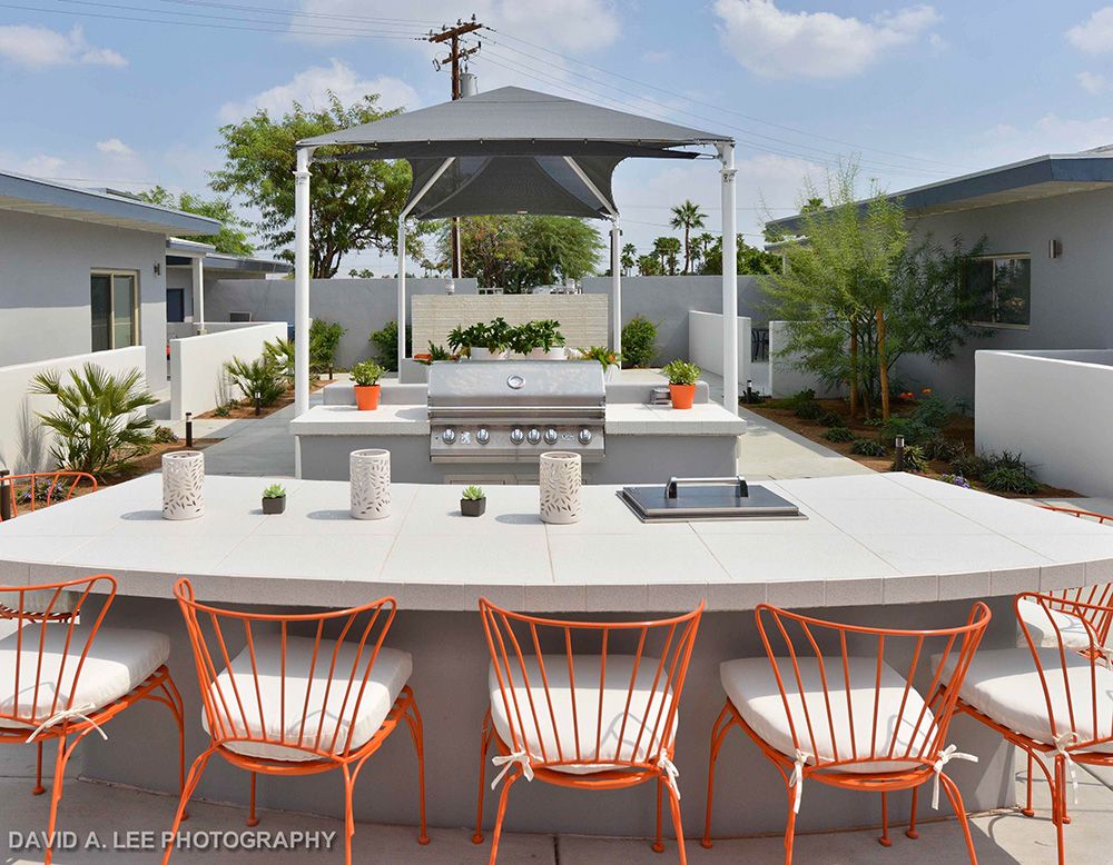 Modern outdoor patio with seating and barbecue area under a shade canopy.