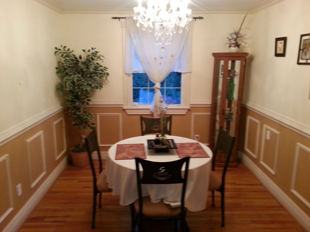 A cozy dining room with a round table and elegant chandelier lighting.