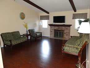 A cozy living room with wooden floors, featuring a fireplace and seating area.