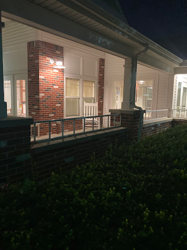 A well-lit residential building captured at night, showcasing its architectural features and surrounding greenery.