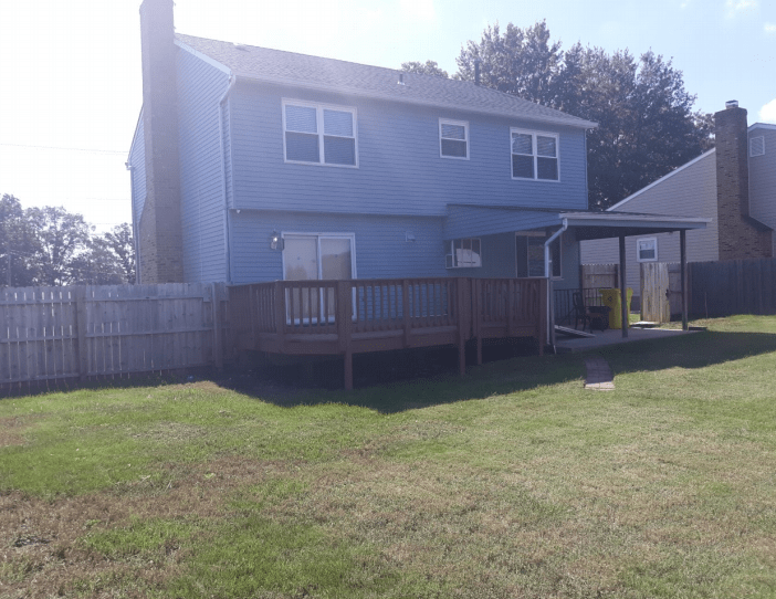 A two-story house with a wooden deck and fenced backyard.