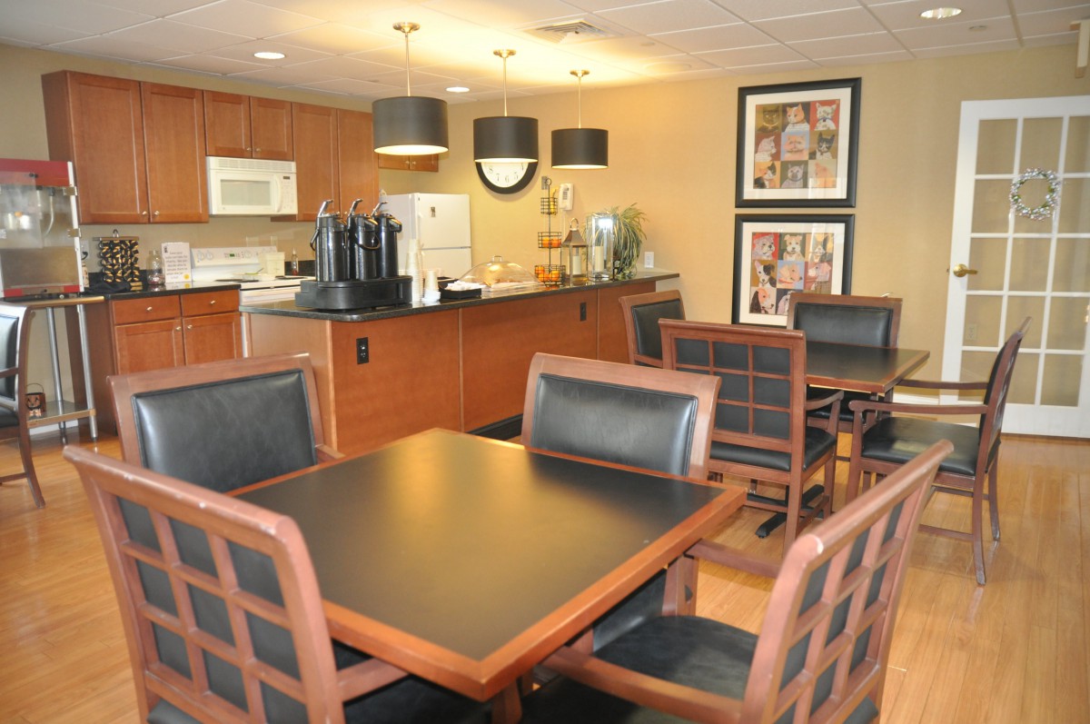 A modern dining area with wooden furniture and kitchen appliances in the background.