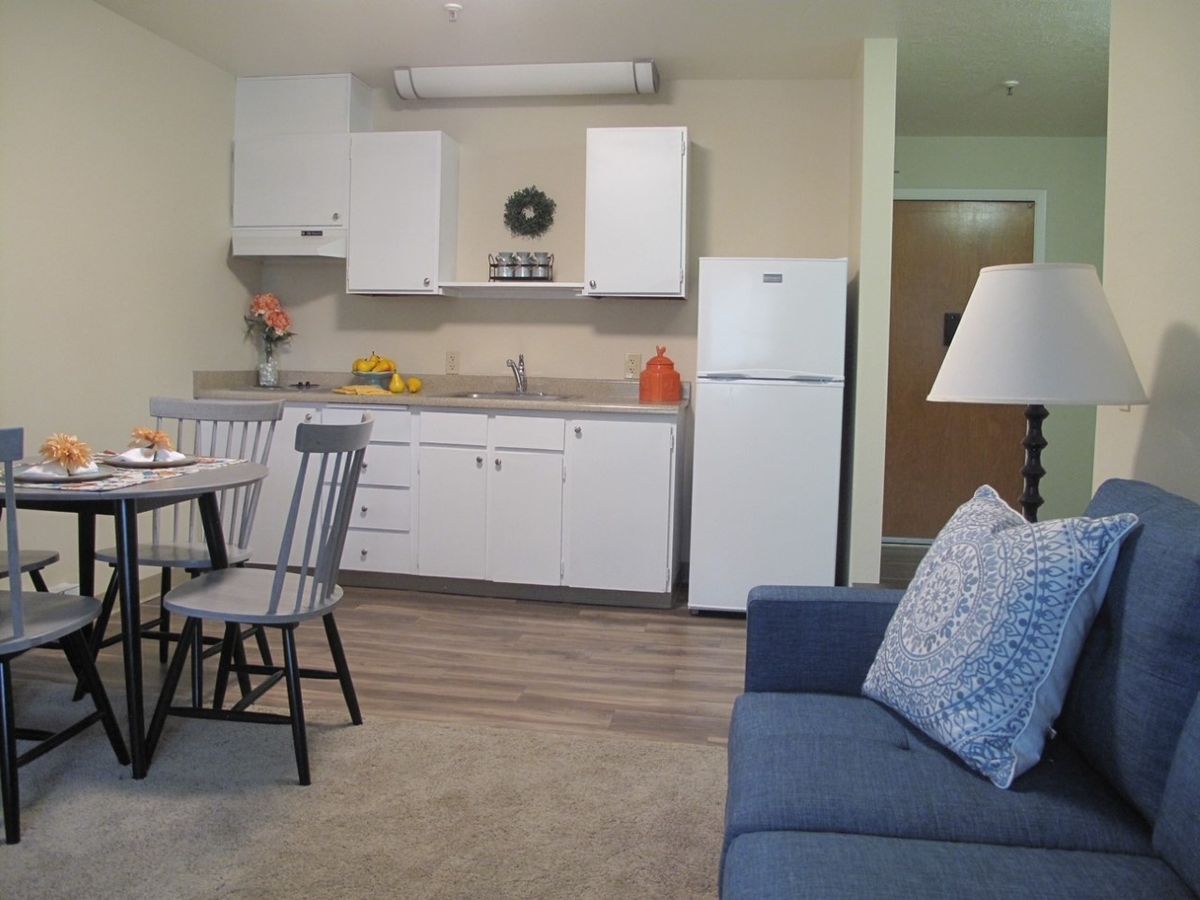 A cozy kitchen and living area featuring a dining table, chairs, refrigerator, and a comfortable sofa.