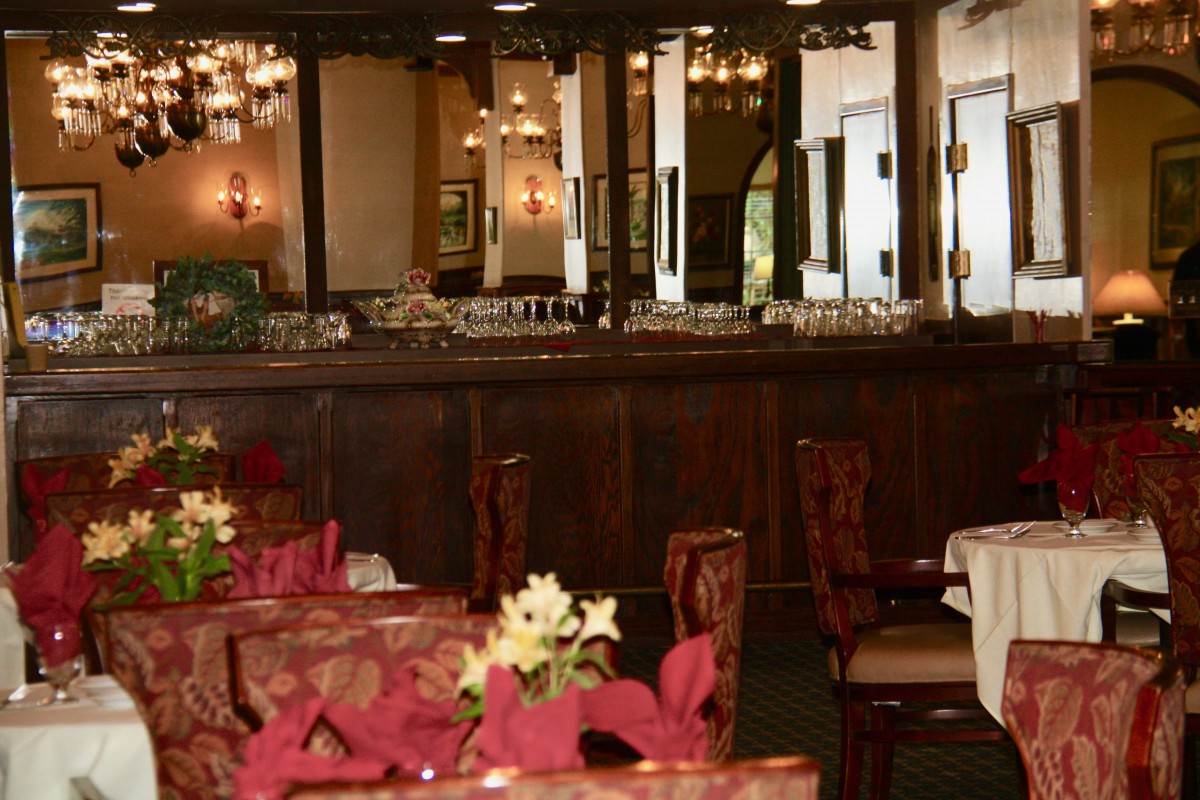 A cozy restaurant interior with elegantly set tables and warm lighting.