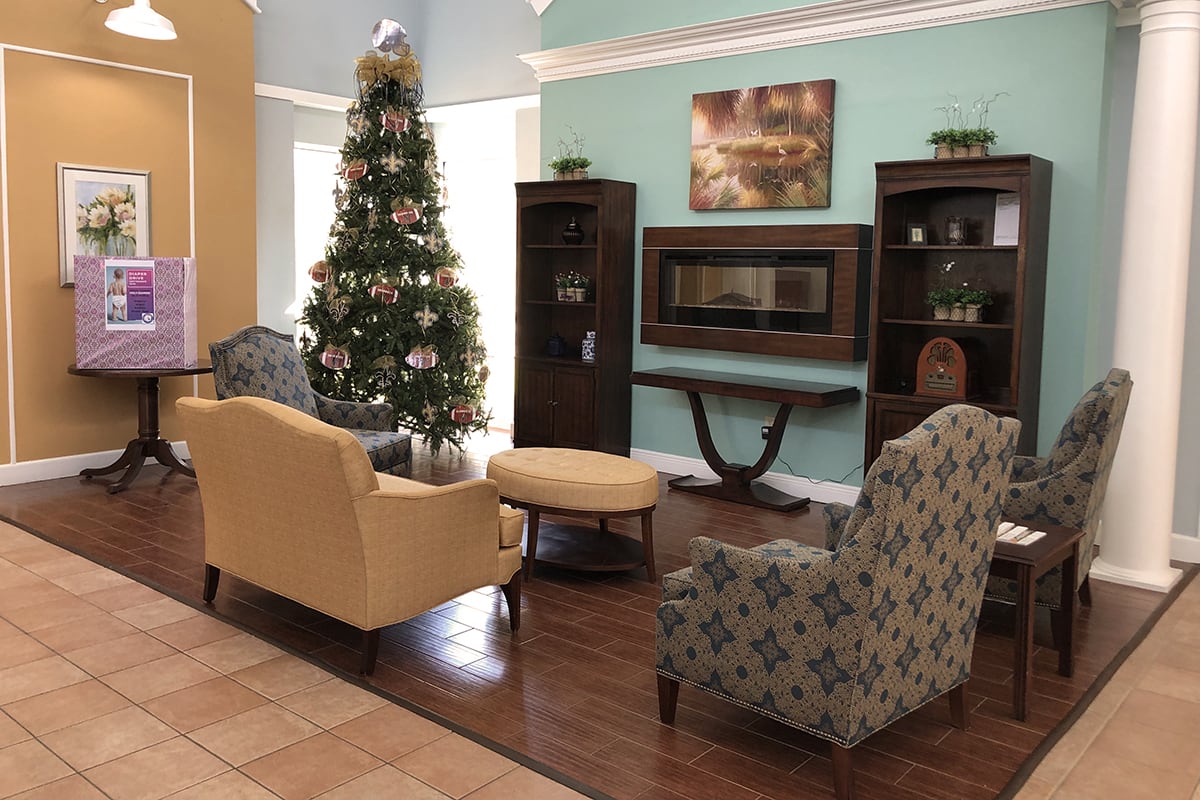 A cozy living room decorated for the holiday season with a Christmas tree, comfortable seating, and a fireplace.