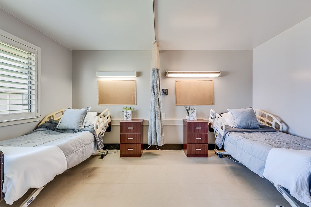 A clean and organized hospital room with two patient beds separated by a curtain.