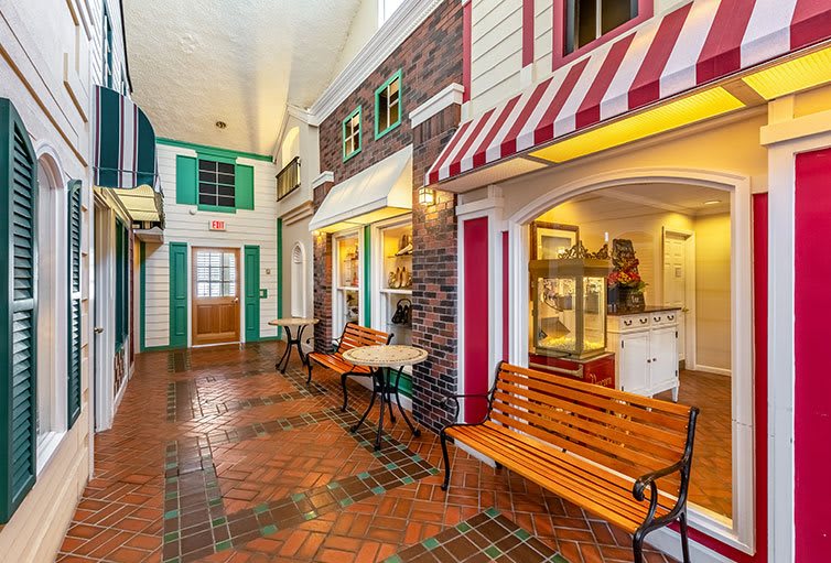 A charming indoor walkway featuring decorative storefronts and cozy seating.