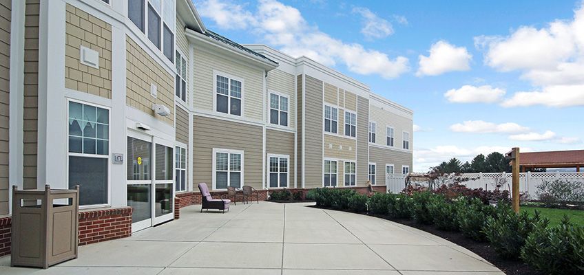 A modern residential building with a large, open patio area under a cloudy sky.