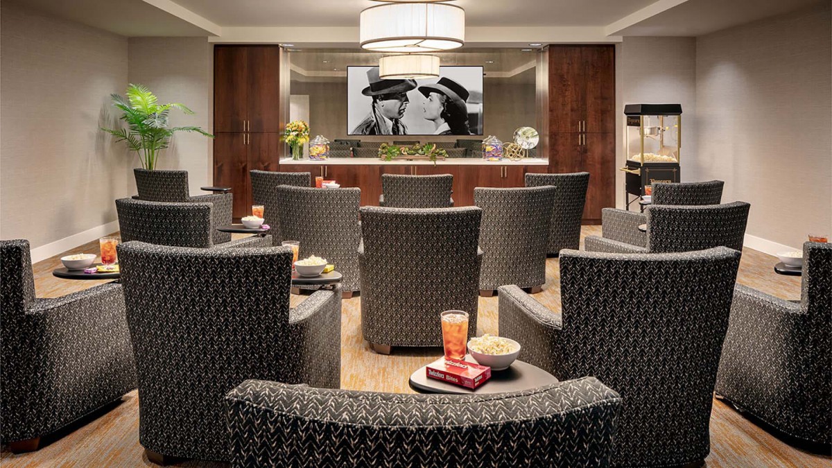 A cozy lounge area with comfortable seating, a large movie screen, and snacks ready for enjoyment.