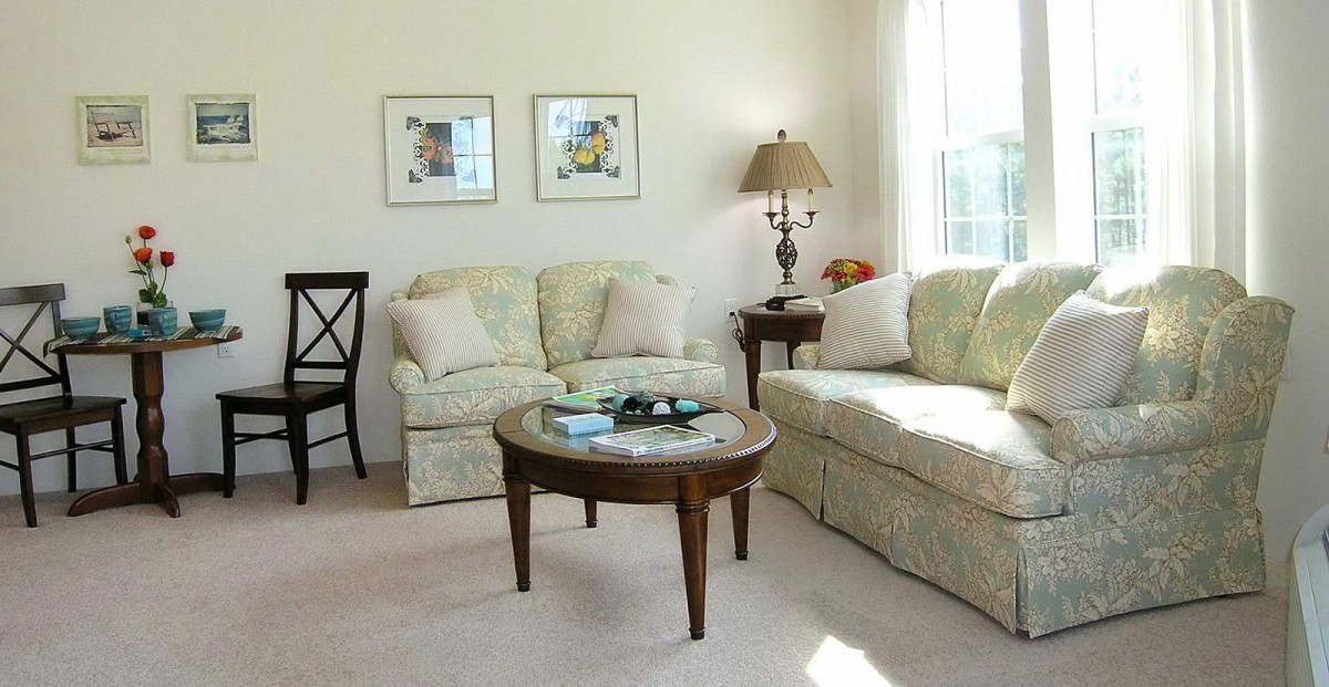 A cozy living room featuring a comfortable sofa, a wooden coffee table, and framed artwork on the wall.