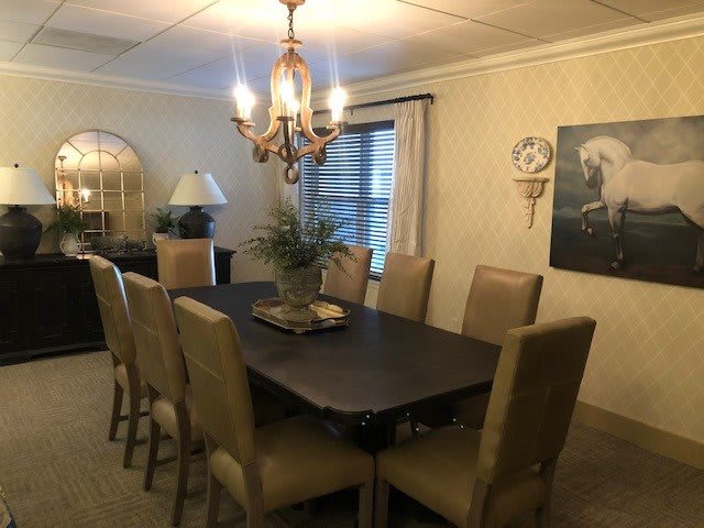 A well-appointed dining room featuring a large table with eight chairs and an elegant chandelier.