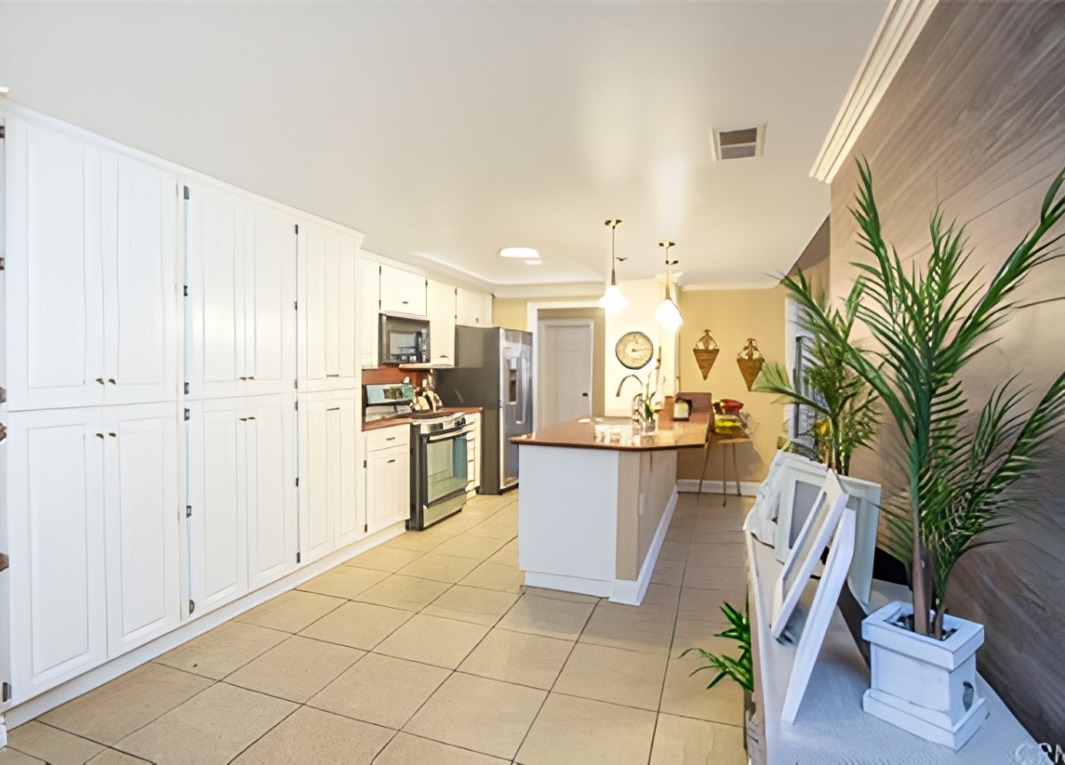 A modern kitchen with white cabinets, a central island, and stainless steel appliances.
