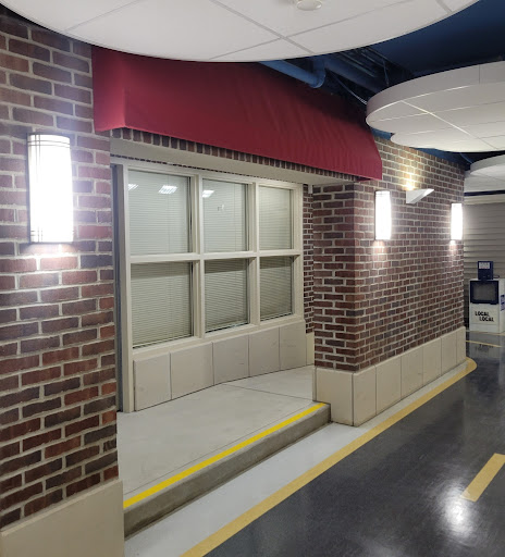 A view of a well-lit corridor featuring a brick wall and a window with steps leading up to it.