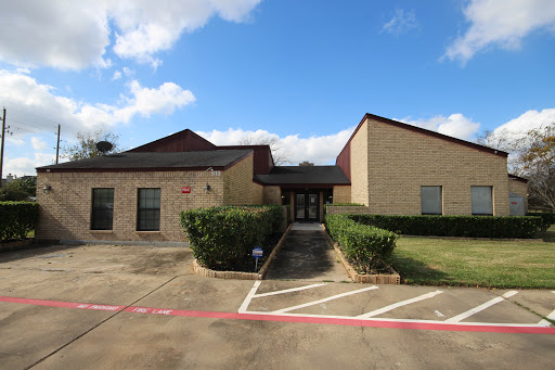 A well-designed building with a landscaped entrance under a bright blue sky.