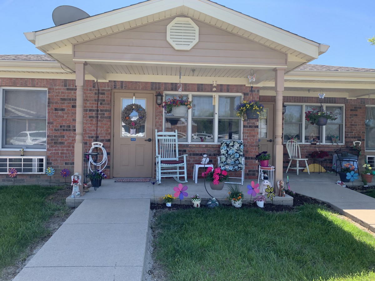A cozy house with a welcoming porch adorned with flowers and a rocking chair.