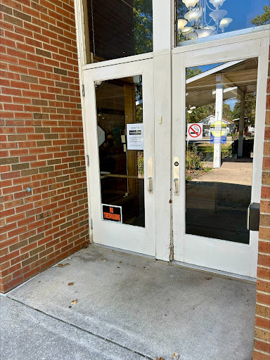 Main entrance with double doors leading into a building, featuring brick walls and informational signage.