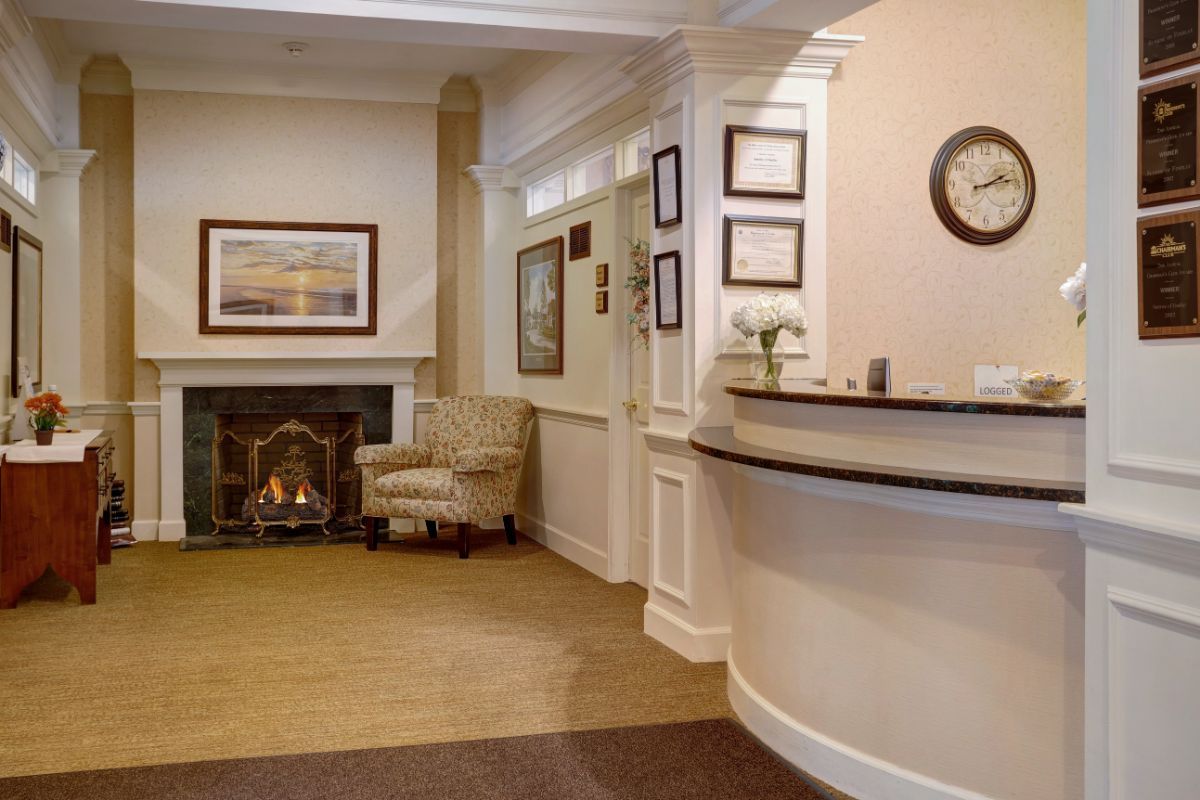 A cozy hotel reception area featuring a desk, comfortable seating, and a small fireplace.