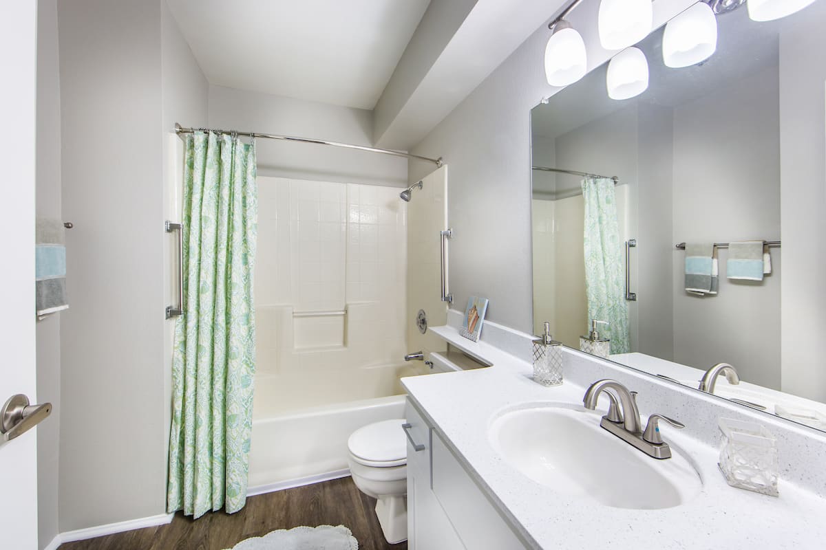 A modern bathroom with a large mirror, sink, and shower area.