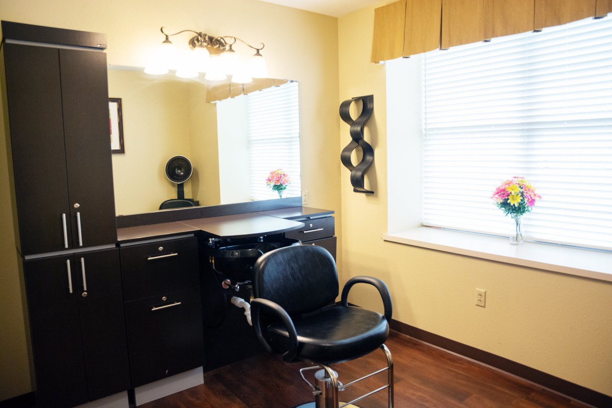 A well-lit hair salon station with a styling chair and mirror.