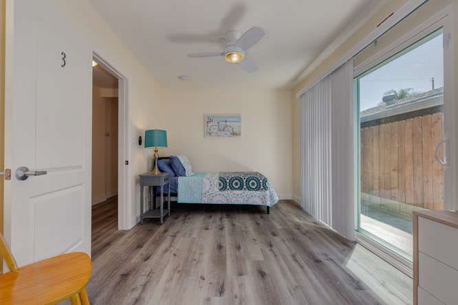 A minimalist bedroom with a single bed, modern decor, and ample natural light from the sliding door.