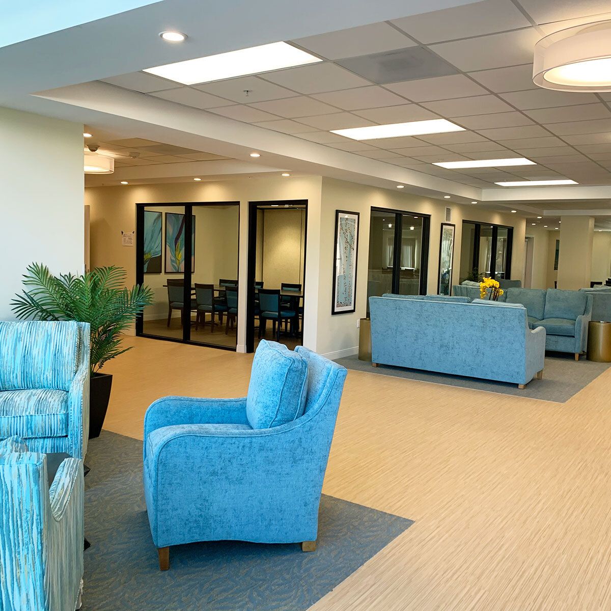 A modern waiting room with blue upholstered seating and bright lighting.