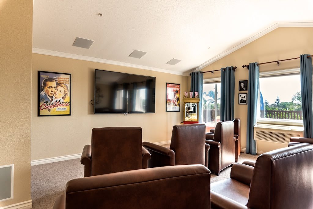 A cozy home theater room with comfortable seating and a large screen, complemented by movie posters on the walls.