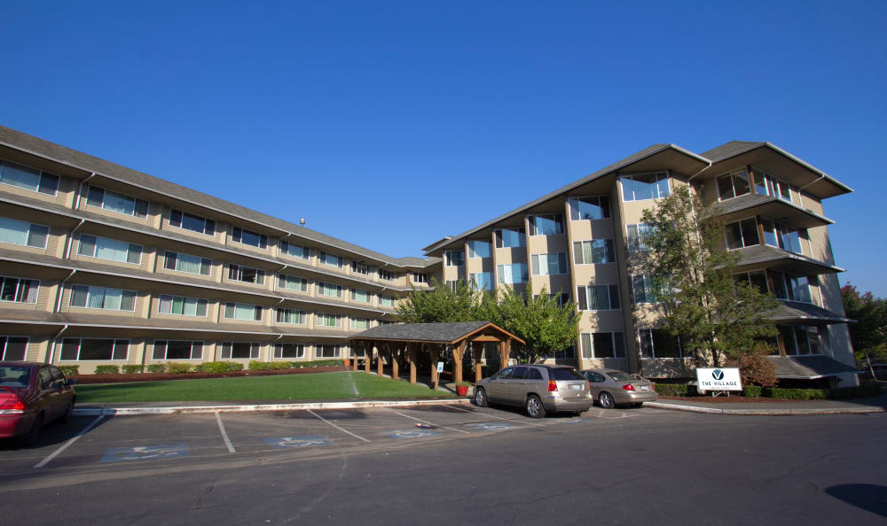 A modern apartment building with a parking lot on a clear, sunny day.
