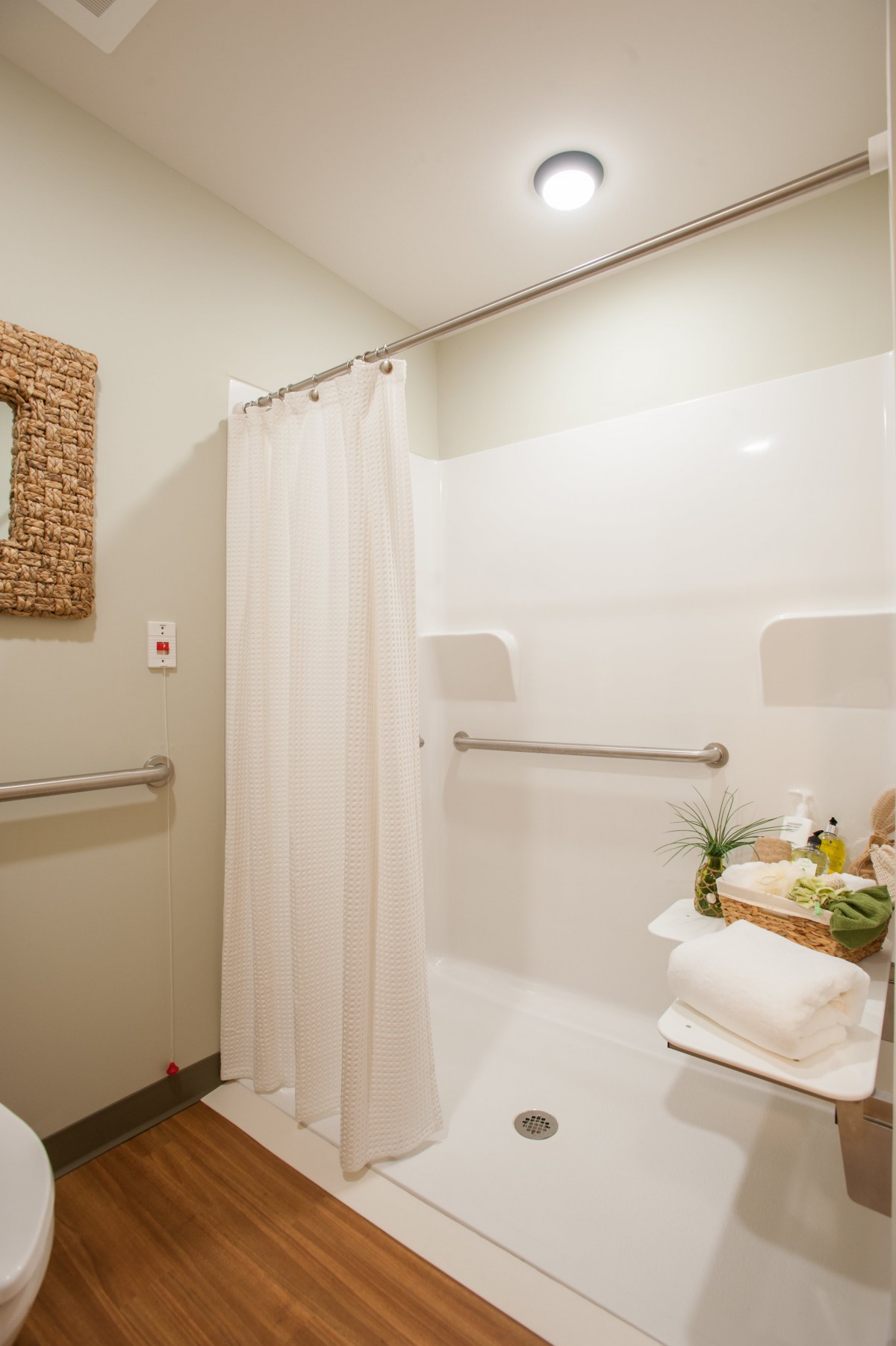 A clean and minimalist bathroom with a shower, curtain, towels, and decorative mirror.