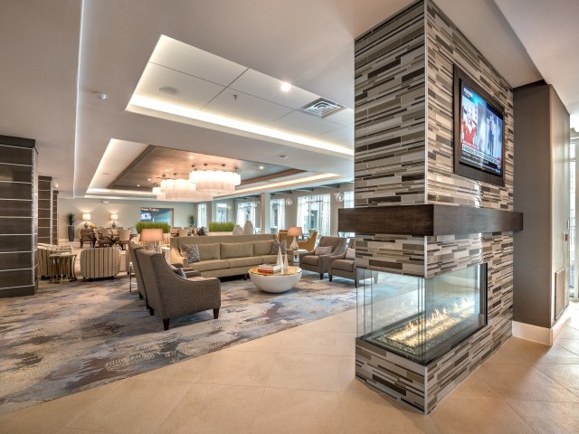 A modern lounge interior featuring a fireplace, comfortable seating, and a chandelier.
