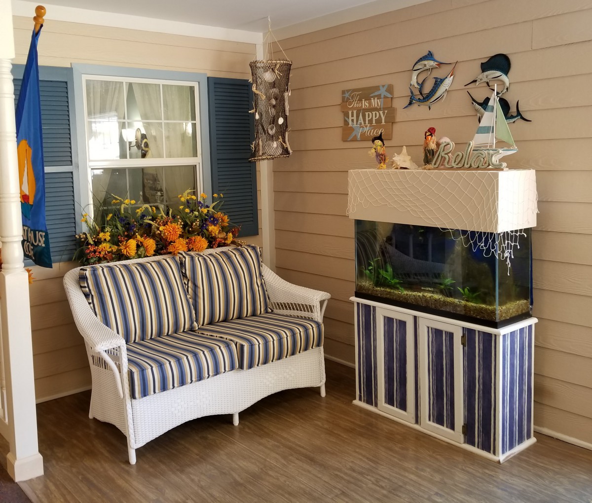 A cozy living room interior featuring a striped sofa and an aquarium with nautical-themed decorations.