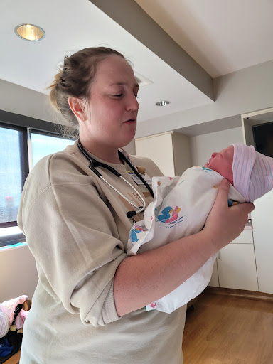 A nurse gently holds a newborn baby in a hospital setting.