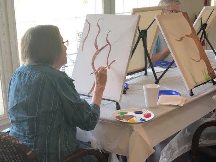 A person engaged in painting during an art class session.