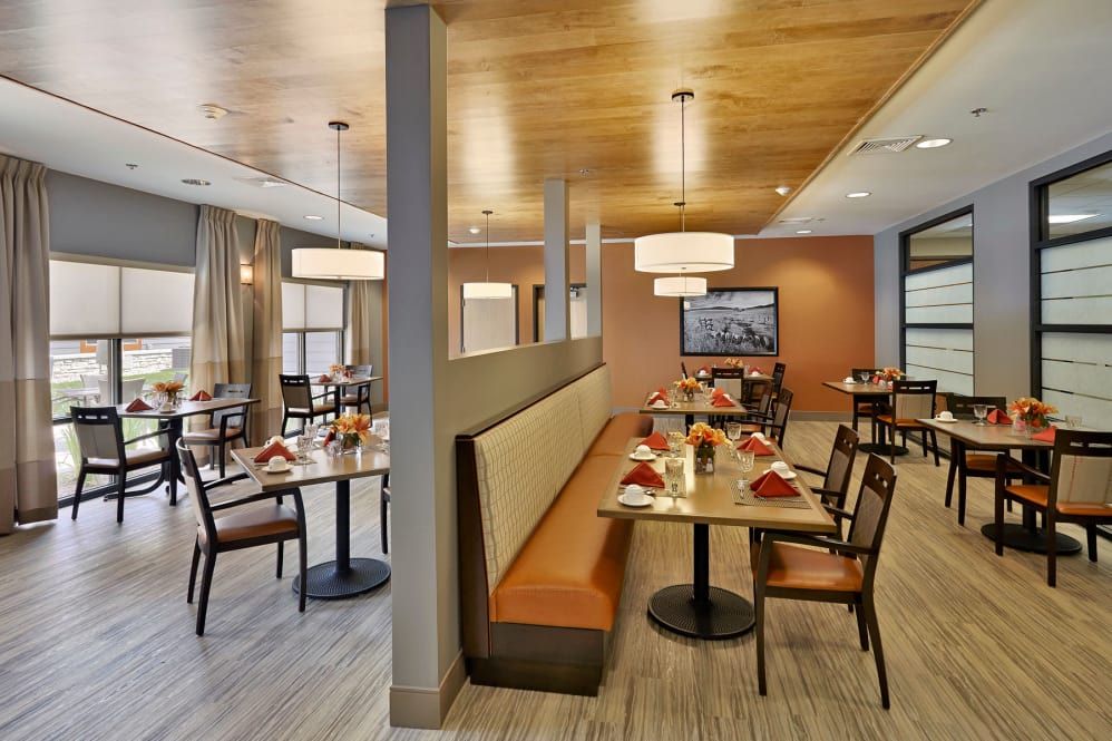 A well-lit restaurant dining area with tables and booth seating, featuring modern decor and warm lighting.