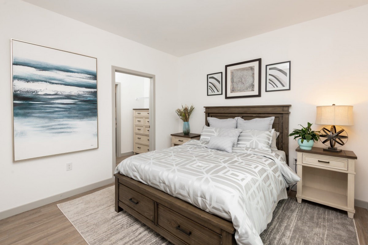 A modern bedroom with a neatly made bed, stylish decor, and artwork on the walls.