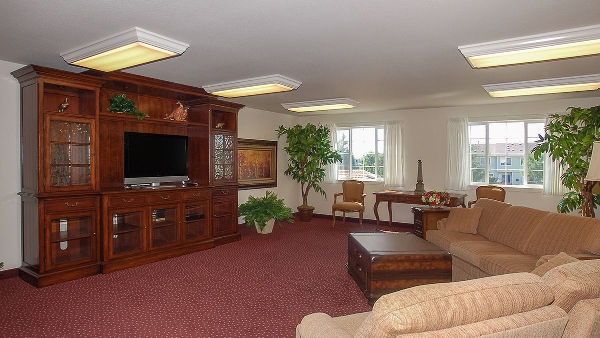 A spacious living room with a large television, comfortable seating, and natural light.