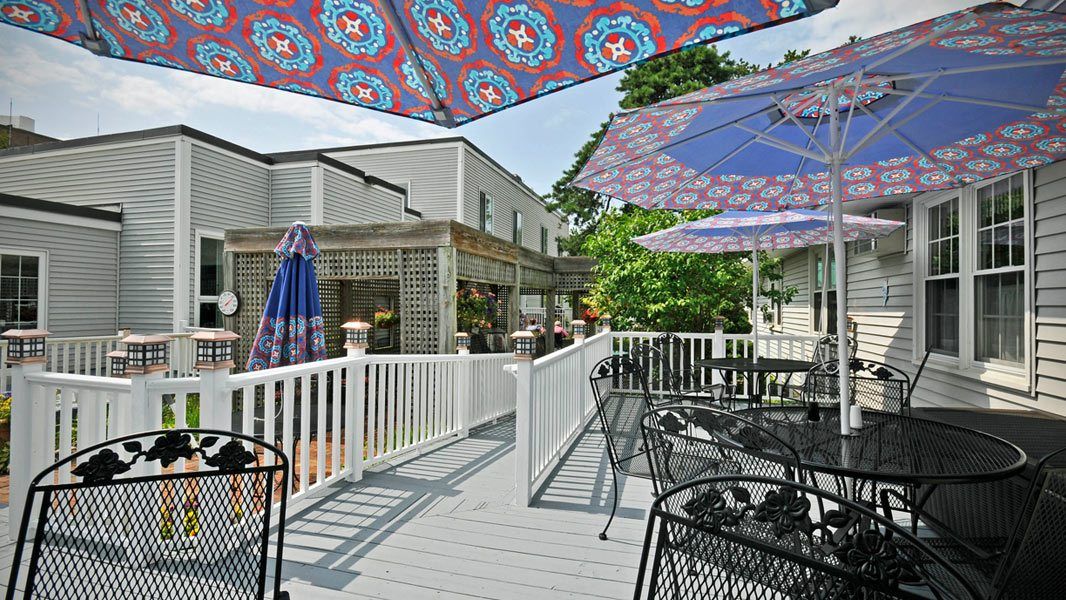 A sunny outdoor deck featuring colorful umbrellas, tables, and chairs.