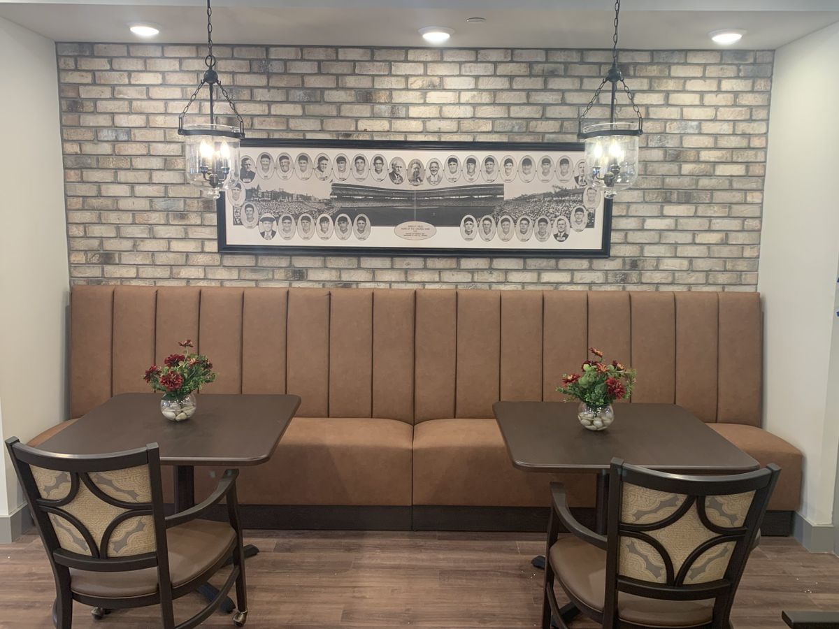 A cozy restaurant interior featuring booth seating, a brick wall backdrop, and ambient hanging lights.