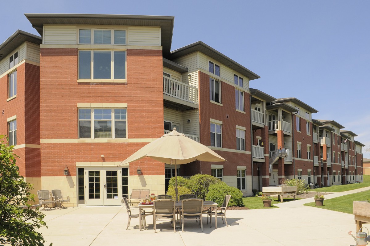 A modern apartment building with a patio area featuring outdoor seating.