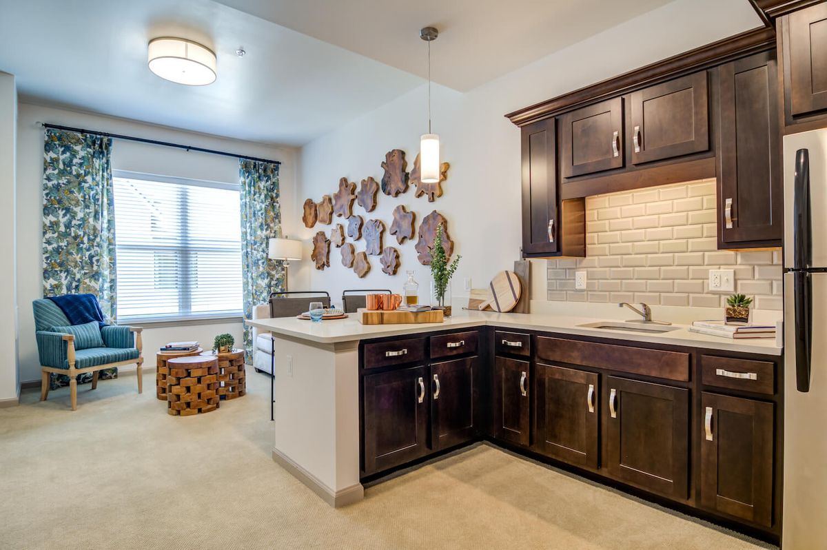 A modern kitchen with dark cabinets, decorative wall art, and ample natural light.