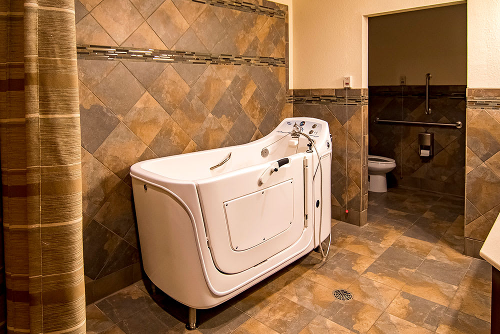 A bathroom featuring a walk-in tub with tiled walls and floor.