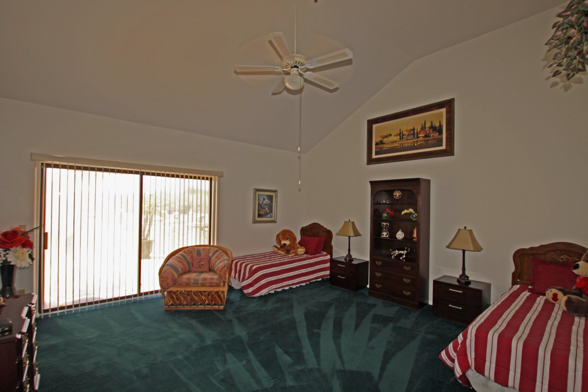 A spacious bedroom with twin beds, carpeted floor, and cozy furniture.