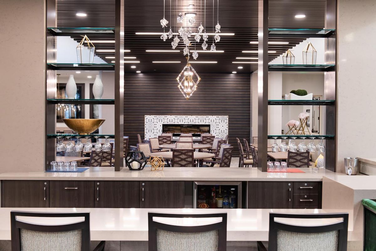 A luxurious and modern kitchen with a chandelier and open shelving, leading to a dining area.