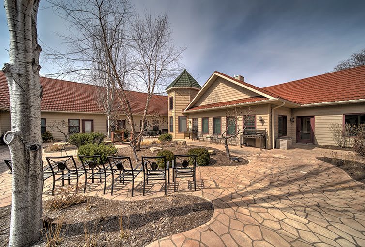 A serene courtyard featuring outdoor seating and landscaping, surrounded by a rustic building.