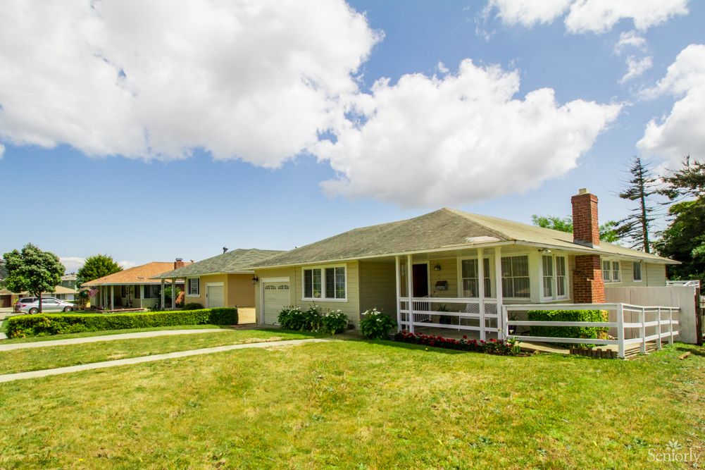 A suburban house with a well-maintained lawn under a partly cloudy sky.