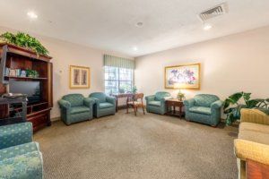 A cozy living room with green armchairs and paintings on the walls.
