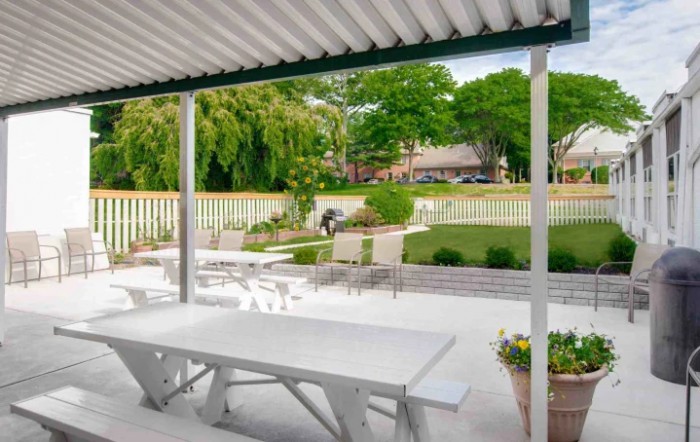 A serene outdoor patio area with a dining table, overlooking a well-maintained garden and yard.