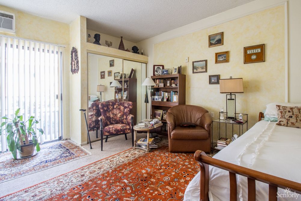 A cozy living room featuring a leather armchair, patterned carpet, and various wall decorations.