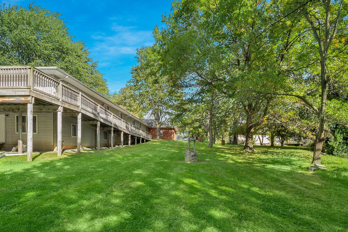 A spacious backyard with a large lawn, surrounded by trees and featuring an elevated deck.