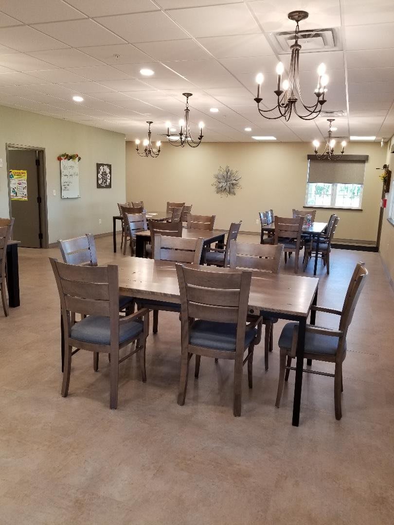 A spacious and elegantly decorated dining room with multiple tables and chandeliers.